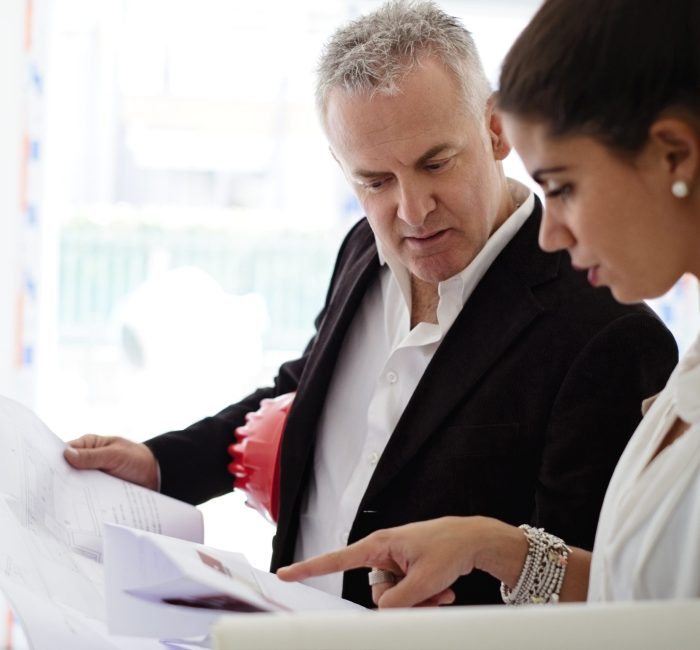 Expert people working in construction site. Man and woman at work as architects in new apartment building, checking blueprint during business meeting