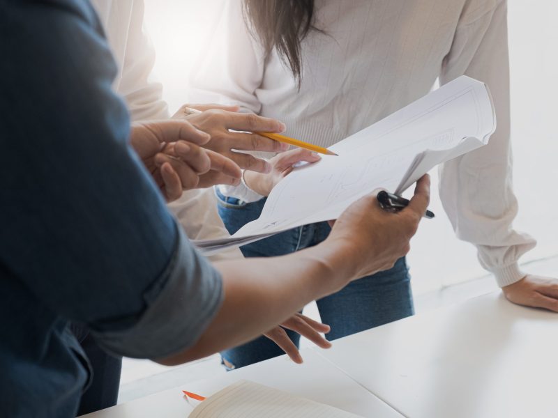 business people group on meeting and presentation in bright modern office with construction engineer architect and worker looking building model and blueprint plans.